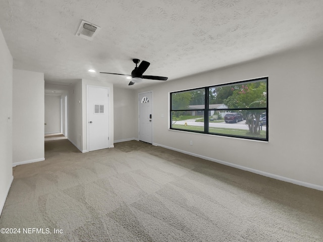 carpeted empty room featuring a textured ceiling and ceiling fan