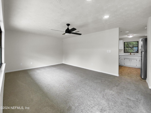 unfurnished room featuring a textured ceiling, ceiling fan, and carpet