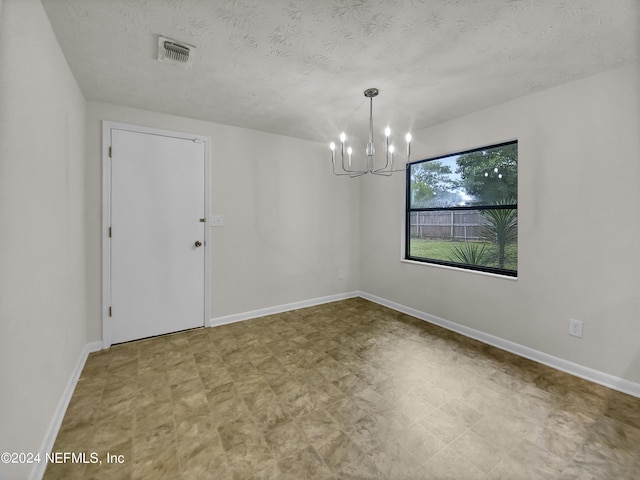 unfurnished dining area with a textured ceiling and a notable chandelier