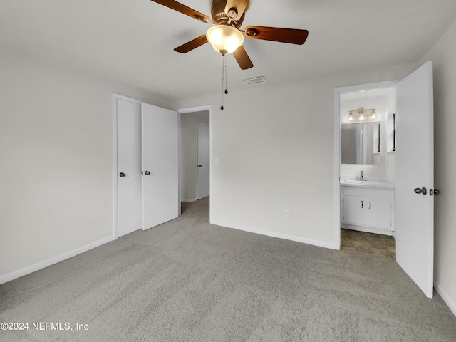 unfurnished bedroom featuring ensuite bathroom, a closet, ceiling fan, light carpet, and sink