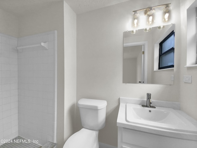 bathroom featuring a tile shower, vanity, toilet, and a textured ceiling