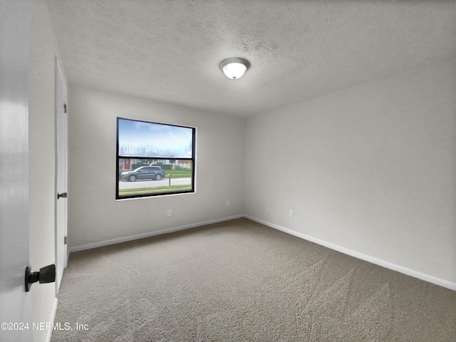 spare room featuring a textured ceiling and carpet