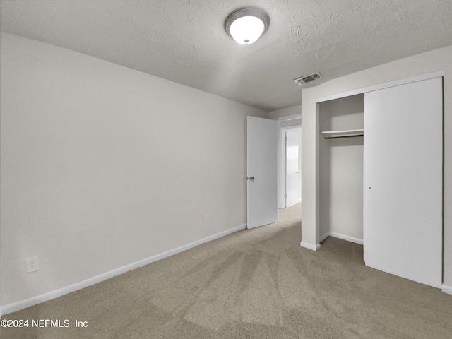 unfurnished bedroom with a textured ceiling, a closet, and carpet flooring