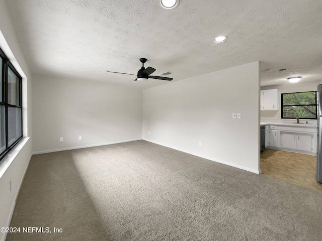 interior space with a textured ceiling, light carpet, and ceiling fan