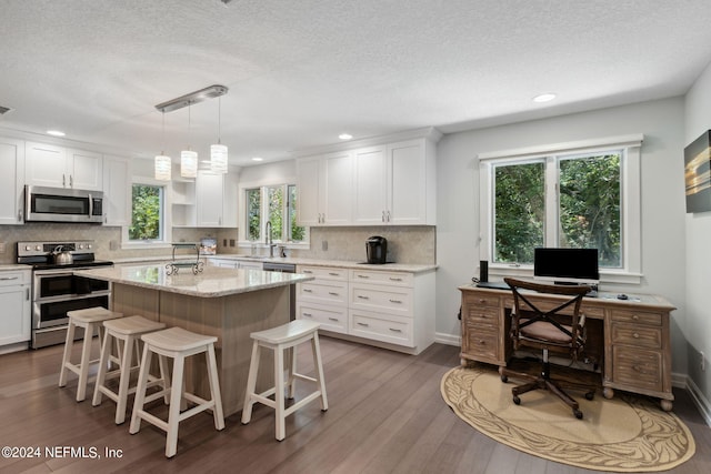 kitchen with white cabinets, stainless steel appliances, and hanging light fixtures