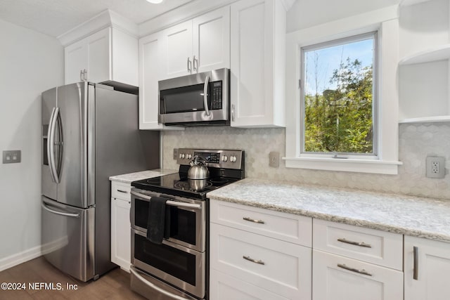 kitchen featuring stainless steel appliances, light stone countertops, and white cabinets