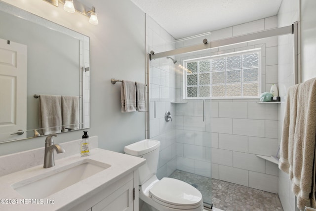 bathroom featuring a textured ceiling, vanity, toilet, and a shower with door