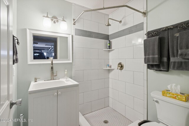 bathroom with tiled shower, vanity, and toilet