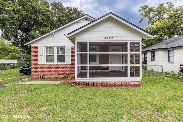 view of front facade with a sunroom and a front yard