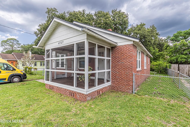 back of house featuring a sunroom and a lawn