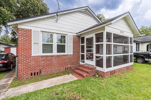 bungalow-style house with a sunroom and a front lawn