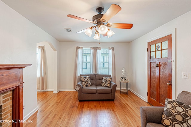 living room with a fireplace, light hardwood / wood-style flooring, and ceiling fan