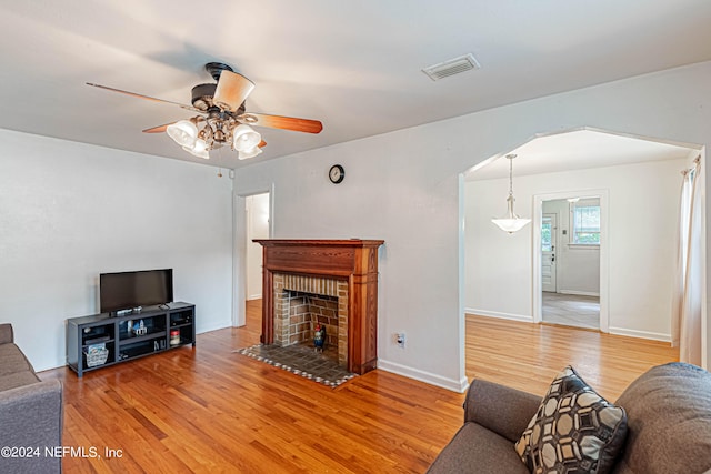 living room with a fireplace, wood-type flooring, and ceiling fan