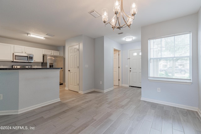 kitchen featuring light wood finished floors, stainless steel appliances, dark countertops, visible vents, and white cabinets