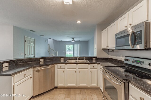 kitchen featuring light wood-type flooring, stainless steel appliances, kitchen peninsula, sink, and ceiling fan