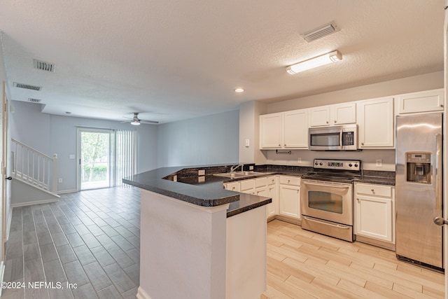 kitchen with appliances with stainless steel finishes, light hardwood / wood-style floors, kitchen peninsula, sink, and ceiling fan