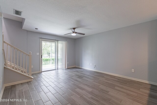 empty room with a textured ceiling, hardwood / wood-style floors, and ceiling fan