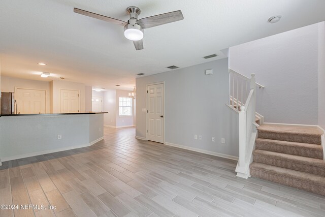 unfurnished living room featuring light wood-type flooring and ceiling fan