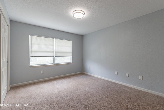 carpeted empty room with a textured ceiling