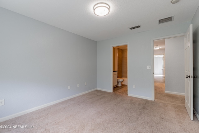 unfurnished bedroom featuring connected bathroom and light colored carpet