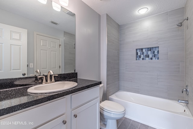 full bathroom featuring tiled shower / bath combo, vanity, toilet, and a textured ceiling