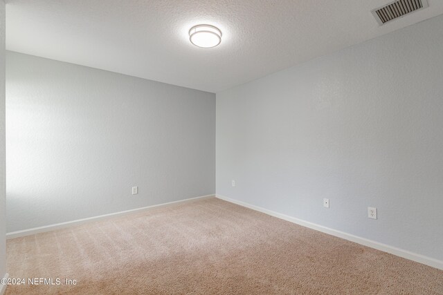 carpeted spare room with a textured ceiling