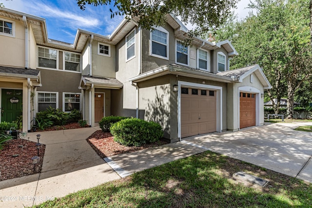 townhome / multi-family property featuring an attached garage, concrete driveway, and stucco siding