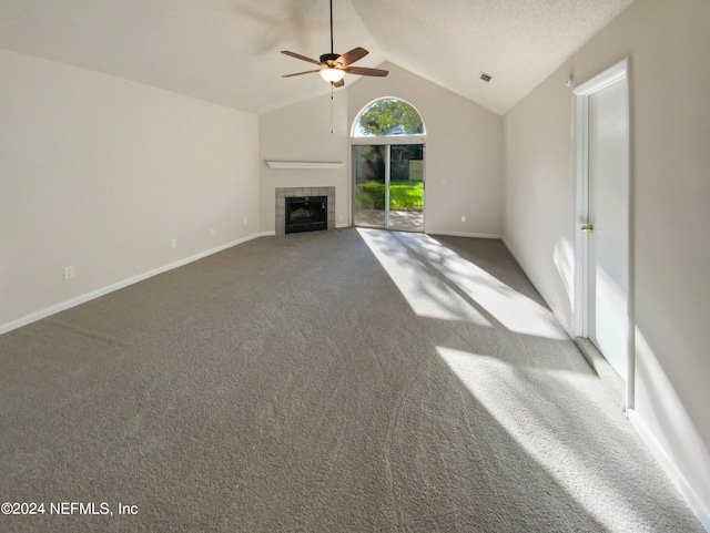 unfurnished living room featuring ceiling fan, carpet flooring, a tiled fireplace, and vaulted ceiling