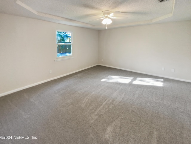 unfurnished room with ceiling fan, a raised ceiling, a textured ceiling, and carpet