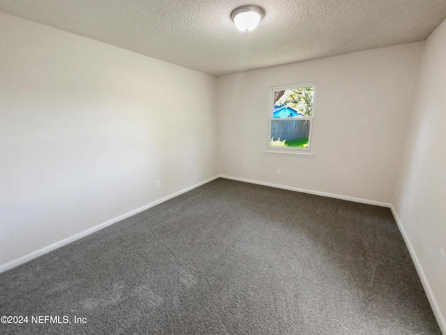 empty room featuring a textured ceiling and dark colored carpet