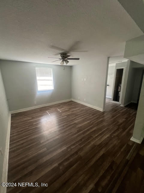 spare room featuring dark wood-type flooring, a textured ceiling, and ceiling fan