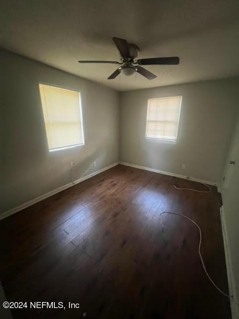 empty room with wood finished floors, a ceiling fan, and baseboards