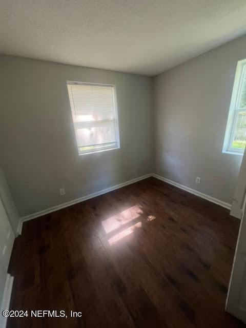 spare room featuring dark wood-type flooring and baseboards