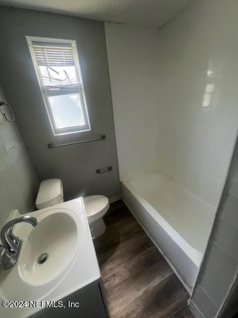 bathroom with a shower, toilet, vanity, wood finished floors, and baseboards