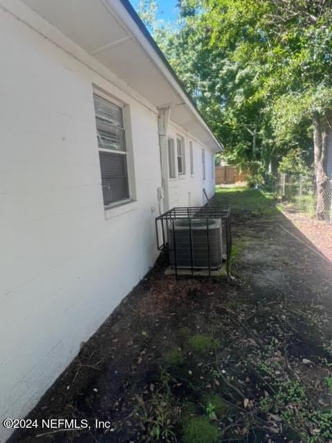 view of property exterior with central AC and fence