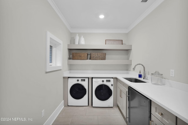 clothes washing area featuring sink, light tile patterned floors, washer and dryer, and crown molding