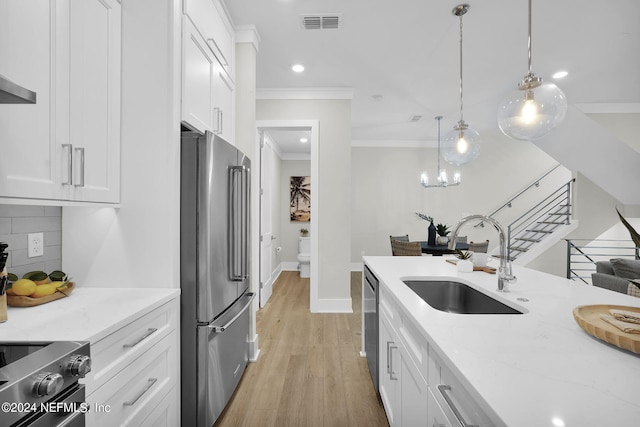 kitchen featuring decorative light fixtures, sink, white cabinets, and stainless steel appliances