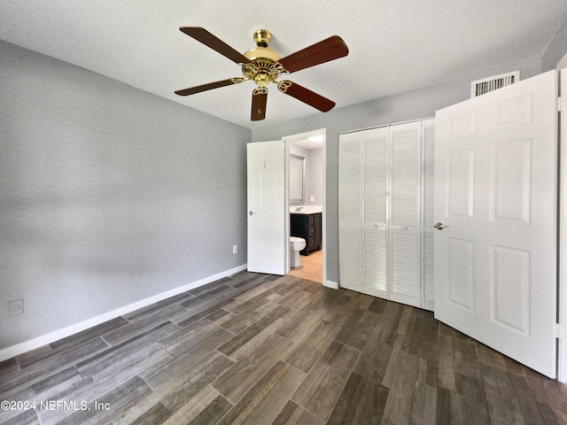 unfurnished bedroom featuring ceiling fan, ensuite bath, and a closet