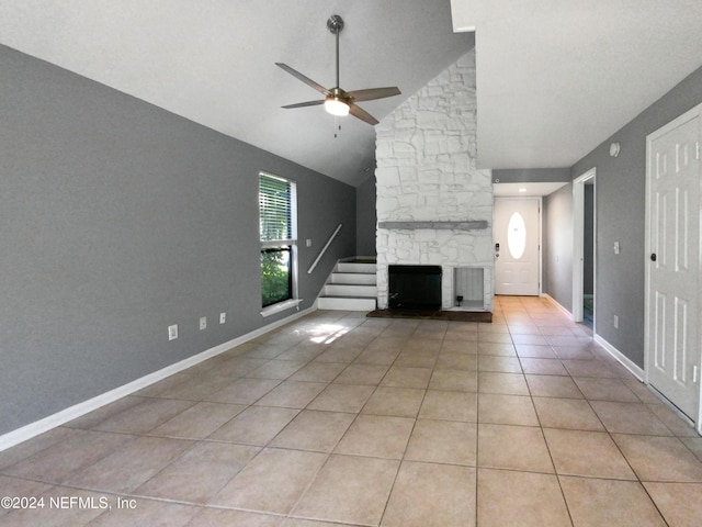 unfurnished living room featuring ceiling fan, light tile patterned floors, a stone fireplace, and high vaulted ceiling