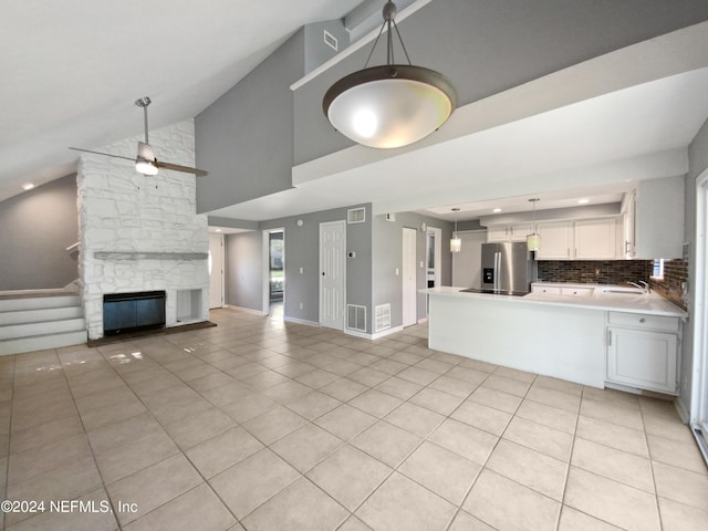 unfurnished living room featuring sink, vaulted ceiling, a stone fireplace, and light tile patterned floors