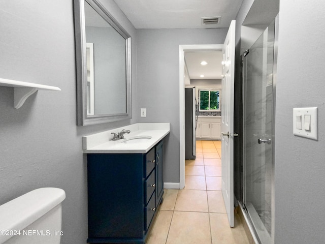 bathroom with tile patterned floors, toilet, vanity, and a shower with door