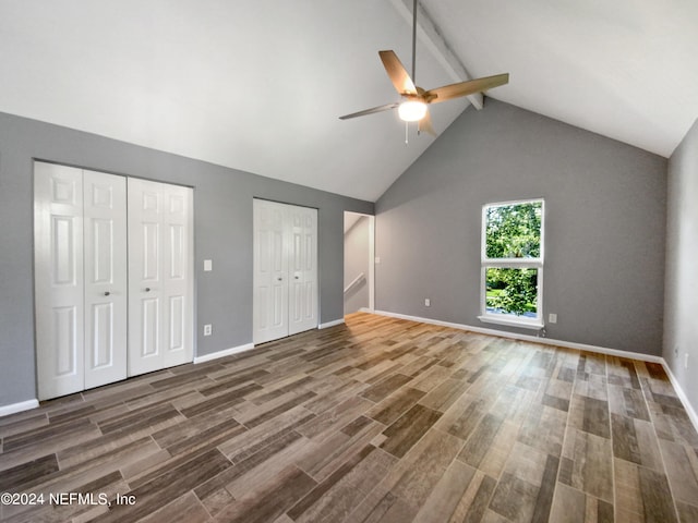 unfurnished bedroom featuring beam ceiling, multiple closets, high vaulted ceiling, ceiling fan, and dark hardwood / wood-style flooring