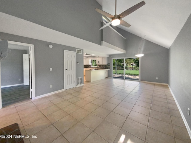 unfurnished living room with high vaulted ceiling, ceiling fan, and light tile patterned floors