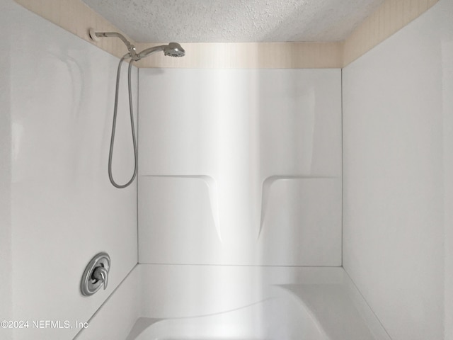 bathroom with a textured ceiling and a shower