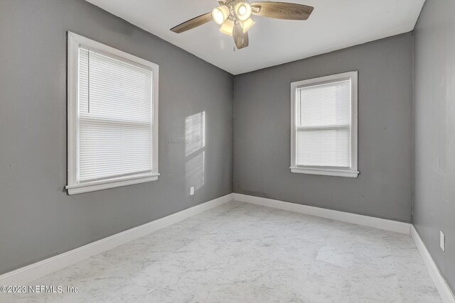 unfurnished room featuring a healthy amount of sunlight and ceiling fan