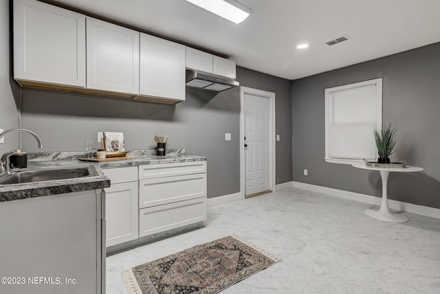 kitchen with white cabinetry, sink, and wall chimney range hood