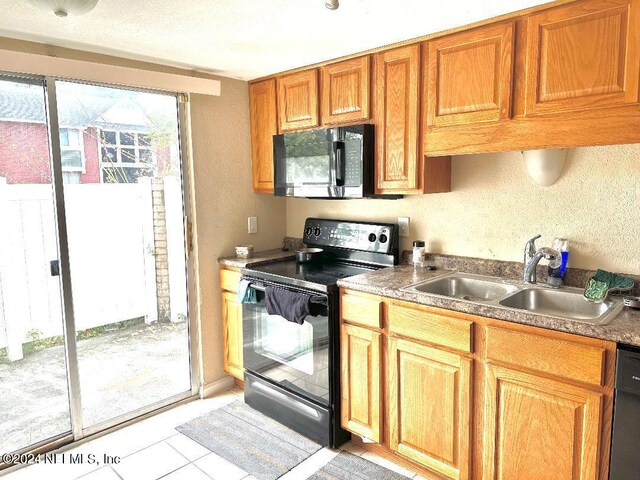 kitchen with light tile patterned floors, a healthy amount of sunlight, black appliances, and sink