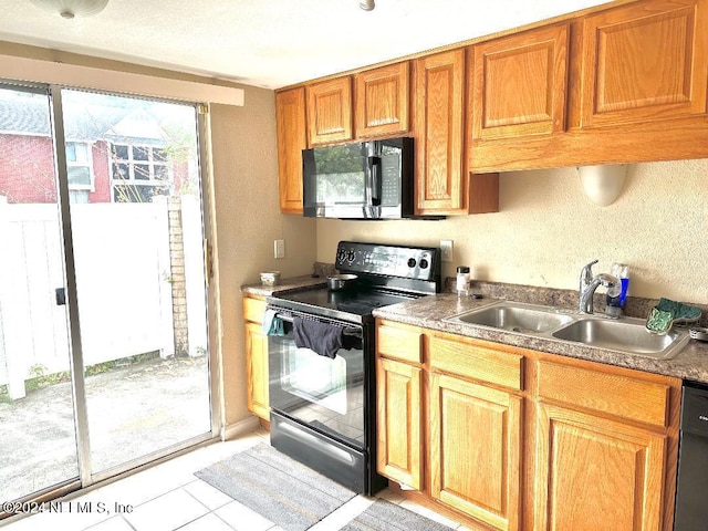 kitchen featuring sink, light tile patterned floors, and black appliances