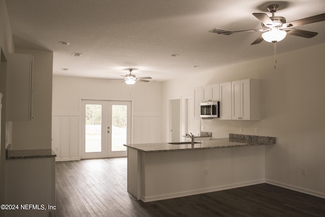 kitchen with white cabinets, kitchen peninsula, french doors, and stone counters