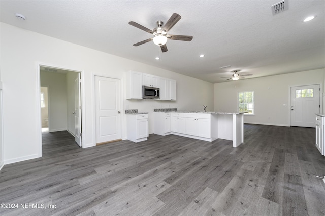 unfurnished living room with ceiling fan, dark wood-type flooring, and a textured ceiling